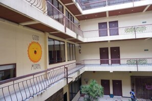 A multi-level atrium with balconies, a sun mural, and a staircase. - King Hotel (Loei)