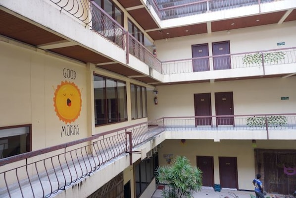 A multi-level atrium with balconies, a sun mural, and a staircase. - King Hotel (Loei)