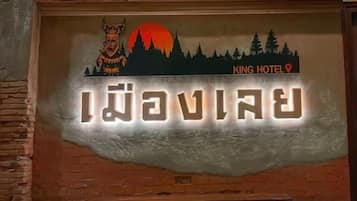 A hotel sign with a logo, name, and location marker.