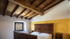 A bedroom with a wooden bed, a nightstand, a dresser, and a window. - Le Chiusure - apartment 'Solaio' (Lake Garda, Lombardy)