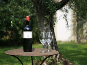 A bottle of wine and two glasses on a round table outdoors.