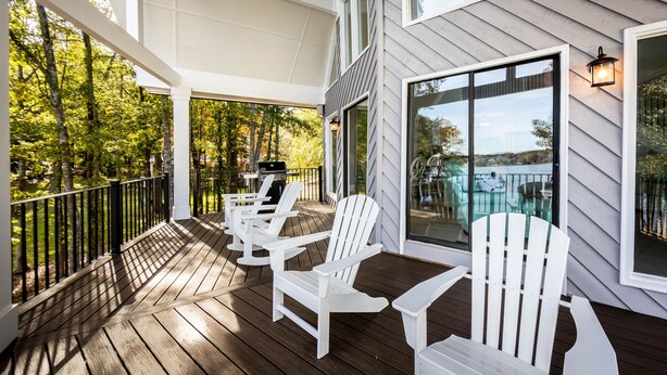 A wooden deck with Adirondack chairs and a glass door leading to a pool area. - Cozy Cottage at Lake Oconee • Walk-Out Patio • Scenic Porch • Sleeps 8 (Eatonton)