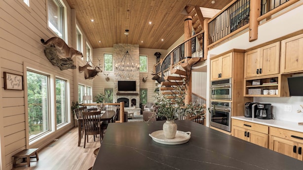 A spacious kitchen with a large island, wooden cabinets, and a stone fireplace.