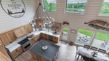 Une cuisine moderne avec des meubles en bois, un îlot central et un coin repas offrant une vue sur l’extérieur.