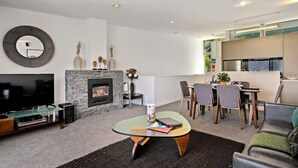 Ein modernes Wohnzimmer mit Kamin, Flachbildfernseher und Essbereich mit Stühlen und Tisch.