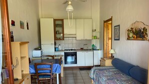 A compact room with a kitchenette, a dining area, and a bed. - Casa Marina (Sardegna)