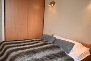 Una camera da letto con un letto, un armadio in legno e una lampada a parete.
