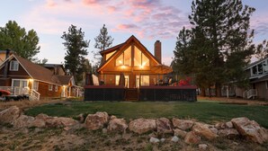A lodge with a prominent wooden structure, a porch, and a stone retaining wall. - 3 Cubs Lakefront Cabin - Lakefront Big Bear Cabin w/ Hot Tub & Game Table (Big Bear Lake)