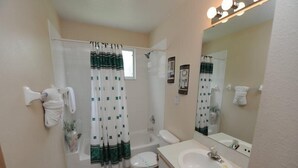 A bathroom with a bathtub, toilet, sink, and a shower curtain. - Condo Disney (Kissimmee)