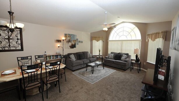 A spacious living room with a dining area, two sofas, a coffee table, and a TV stand. - Condo Disney (Kissimmee)