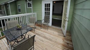 A covered patio with a table and chairs, a sliding glass door, and a white railing. - Condo Disney (Kissimmee)
