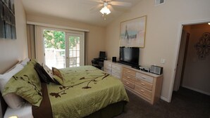 A bedroom with a bed, a desk with a computer, a television, and a ceiling fan. - Condo Disney (Kissimmee)