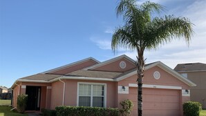 A single-story house with a garage, a small front yard, and a palm tree. - Sandy Ridge 76 (Davenport)