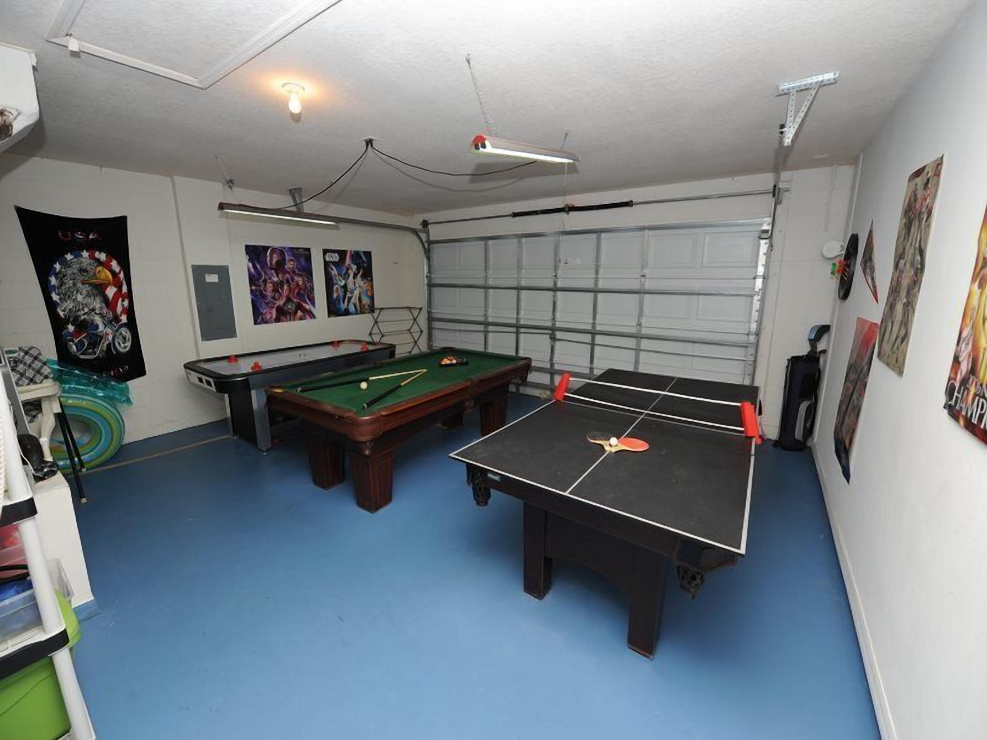 Een kamer met een pooltafel, een pingpongtafel en een biljarttafel.