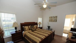 A bedroom with a bed, nightstands, a ceiling fan, a window, and a painting on the wall. - Sandy Ridge 76 (Davenport)