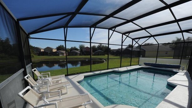 A covered outdoor swimming pool with lounge chairs and a view of a residential area. - Sandy Ridge 76 (Davenport)