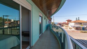 A balcony with a view of the street, a building with a red roof, and a clear sky. - Zancanaro 102- Apto - 641B (Bombinhas)