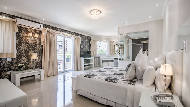 Une chambre à coucher moderne avec un grand lit, des tables de chevet, un bureau et un dressing.