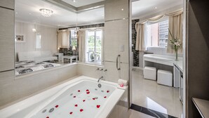 Une salle de bain moderne dotée d’une grande baignoire, d’un espace douche et d’un meuble-lavabo avec un miroir.