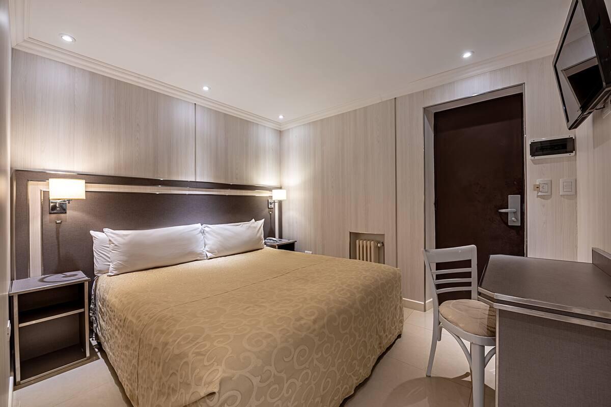 Ein Hotelzimmer mit einem großen Bett, Nachttisch, Stuhl und Schreibtisch.