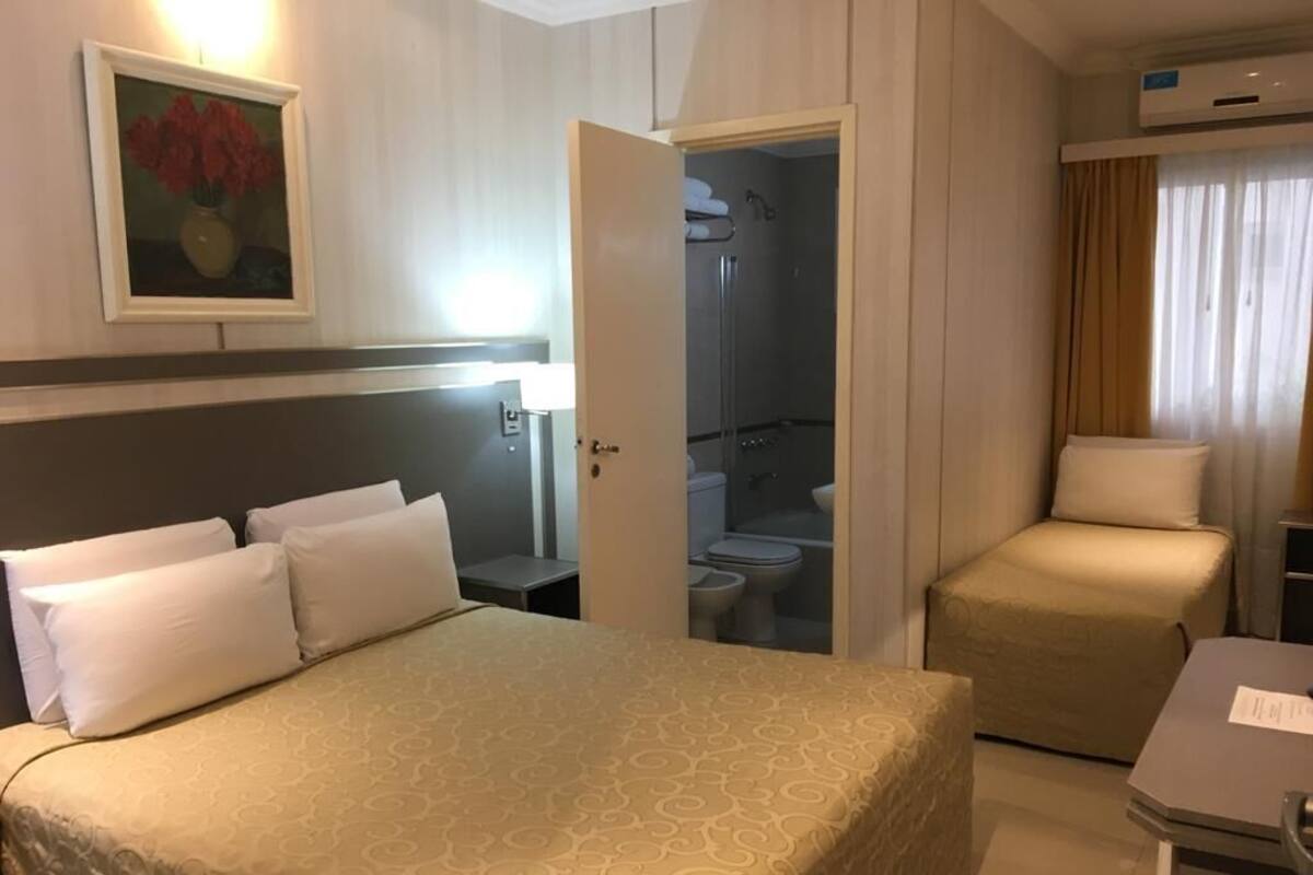 Ein Hotelzimmer mit Bett, Schreibtisch, Stuhl, Dusche und Toilette.