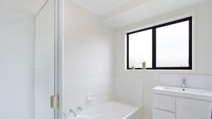Une salle de bain moderne avec une baignoire, une fenêtre et un lavabo.