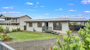 Une maison à deux étages dotée d’un patio couvert, d’une pelouse bien entretenue et d’une allée en gravier.