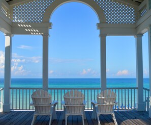 A covered outdoor area with three Adirondack chairs facing a view of the ocean. - Beachside in Seaside, FL! Amazing Gulf Views and Outdoor Spaces + 2 Bikes! (Santa Rosa Beach)