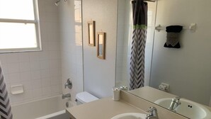 A bathroom with a bathtub, toilet, sink, and a large mirror. - Terra Verde 693 (Kissimmee)