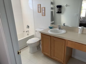 A bathroom with a bathtub, toilet, sink, and wooden cabinets. - Terra Verde 693 (Kissimmee)