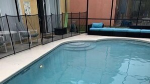 A swimming pool with a black safety fence, a blue lounge area, and a tiled deck. - Terra Verde 693 (Kissimmee)