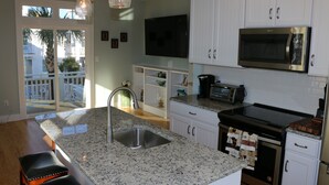 Una cocina con encimeras de granito, electrodomésticos de acero inoxidable y armarios blancos.