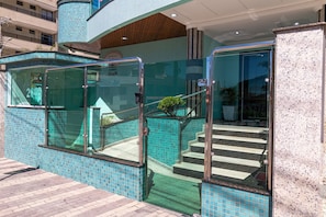 A hotel entrance with glass doors, a tiled wall, and a staircase leading inside. - Zancanaro 203-Apto 641E (Bombinhas)