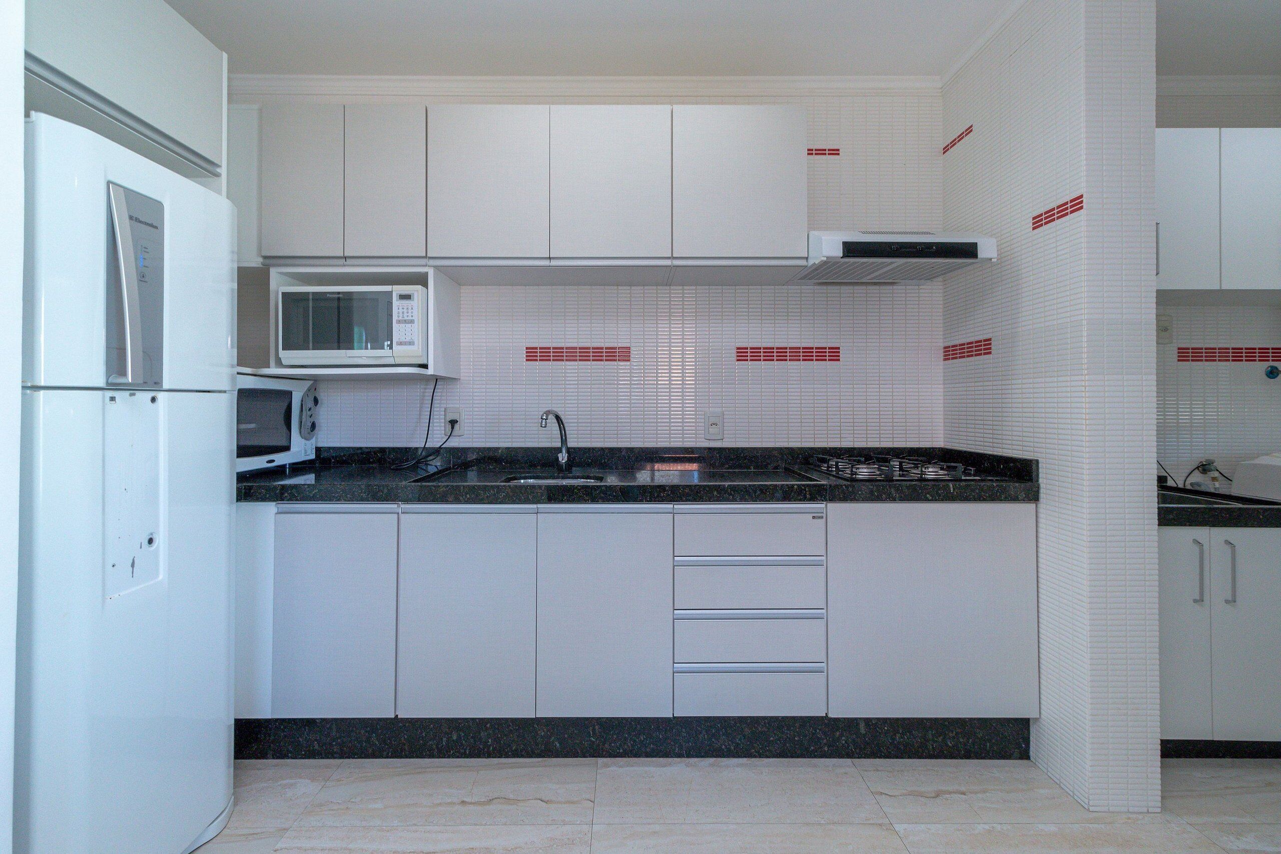 A modern kitchen with white cabinets, a microwave, a sink, and a stove.