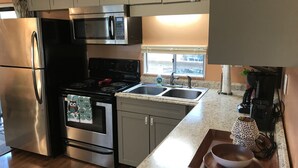 A modern kitchen with stainless steel appliances, a granite countertop, and a window providing natural light. - Waterfront Cottage on the Harris chain in Leesburg  (Leesburg)
