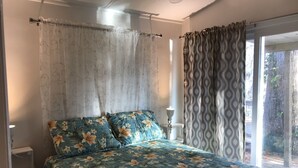 A bedroom with a bed, curtains, and a view of the outdoors. - Waterfront Cottage on the Harris chain in Leesburg  (Leesburg)