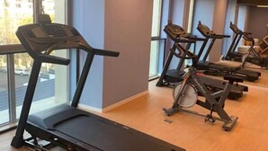 Ein Fitnessstudio mit Laufbändern und Ergometer, großen Fenstern und Holzboden.