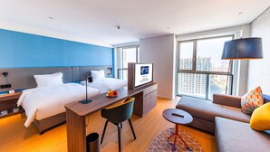 Ein modernes Hotelzimmer mit Bett, Schreibtisch und Sitzgelegenheit.