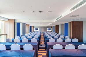 A conference room with rows of tables and chairs, a staircase, and two screens displaying text. - Holiday Inn Express Shanghai Baoshan Baoyang by IHG (Shanghai)