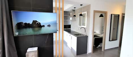 Una cocina moderna con una isla grande, un televisor de pantalla plana montado en la pared y una lámpara colgante sobre la isla.