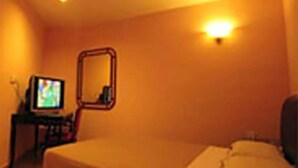 A hotel room with a bed, a television on a stand, and a wall-mounted mirror. - Hotel Reko Inn (Kajang)