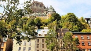 A historic building with a turret and a large central tower, surrounded by trees and other buildings.