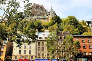 A historic building with a turret and a large central tower, surrounded by trees and other buildings. - Simple and functional loft in the city center (Québec)