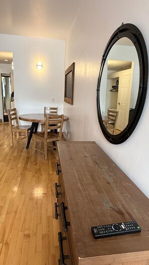 A room with a round mirror, a wooden table, and chairs. - Simple and functional loft in the city center (Québec)
