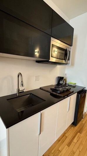 A modern kitchen with a black countertop, stainless steel appliances, and white cabinetry. - Simple and functional loft in the city center (Québec)