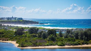 Un paysage côtier comprenant une plage, des affleurements rocheux et une végétation luxuriante.