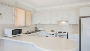 Une cuisine moderne avec des meubles blancs, un four à micro-ondes, un grille-pain, une bouilloire et une cuisinière.