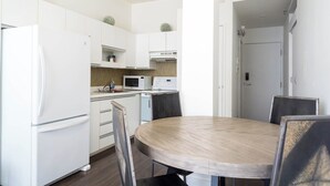 Ett modernt kök med vita skåp, en mikrovågsugn, ett kylskåp och ett matbord med stolar.