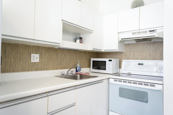 A modern kitchen with white cabinets, a microwave, and a built-in oven.