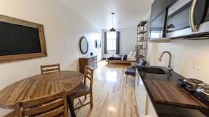 A modern kitchen with a central island, built-in appliances, and a dining area with a round table and chairs.